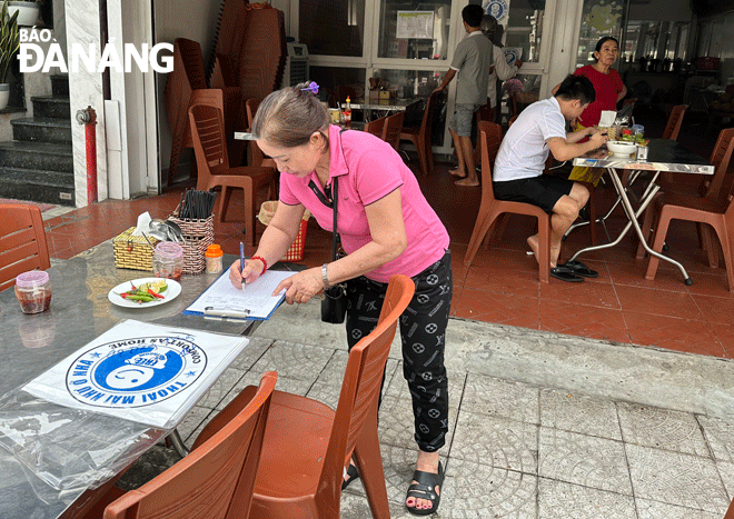 The representative of a family-run establishment in Son Tra District signs a commitment  in writing  and receives the logo of ‘Comfort as home’. Photo: CAO MINH