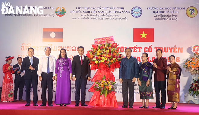 Phó Chủ tịch thường trực UBND thành phố Hồ Kỳ Minh (thứ 4, từ trái qua) và Phó Chủ tịch HĐND thành phố Nguyễn Thị Anh Thi (thứ 3, từ trái qua) tặng hoa chúc mừng Tết Bunpimay Lào năm 2023 