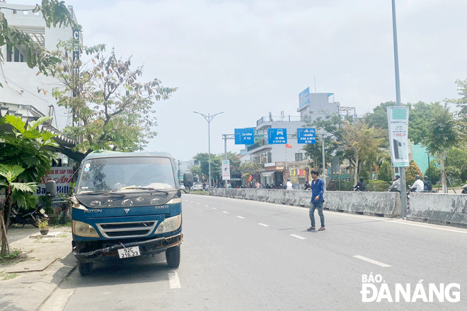 Một người dân vượt qua các dải phân cách để băng qua đường Hoàng Văn Thái, phường Hòa Khánh Nam, quận Liên Chiểu. Ảnh: CHIẾN THẮNG	