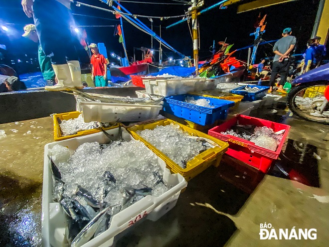 Baskets of flying fish are brought ashore by fishermen to wait for traders