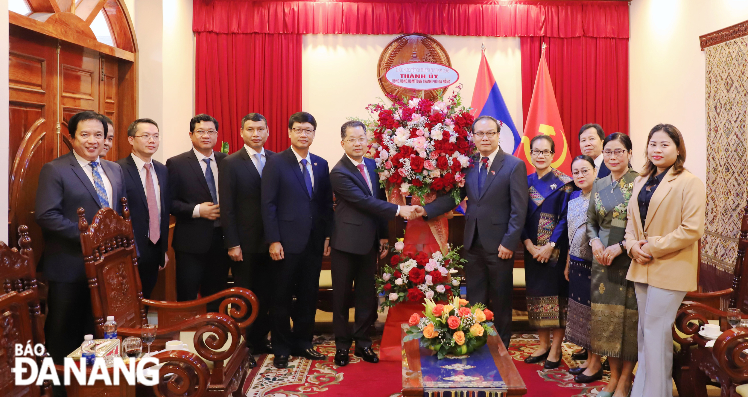 Da Nang Party Committee Secretary Nguyen Van Quang (6th, left) presents flowers to congratulate officials and employees of the Lao Consulate General in Da Nang on the occasion of Laos' New Year festival Bunpimay 2023. Photo: NGOC PHU