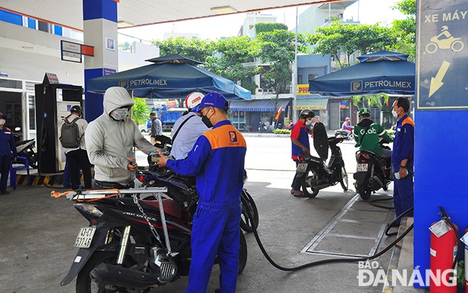 A local customer has his motorbike filled up at a petrol station in Da Nang 