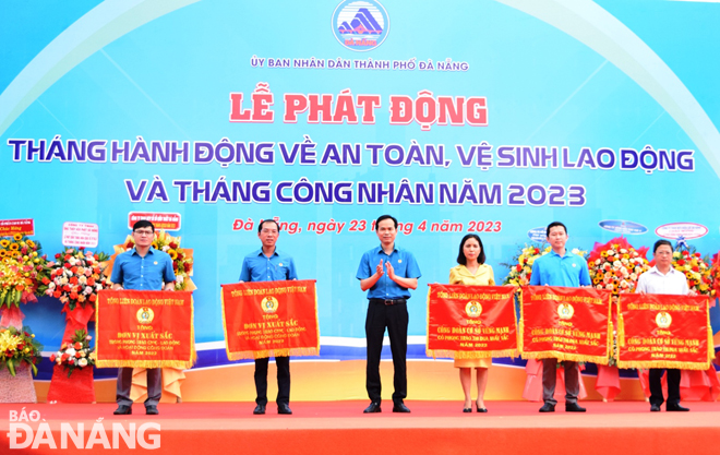 Chủ tịch Liên đoàn Lao động thành phố trao cờ thi đua của Chủ tịch Tổng Liên đoàn Lao động Việt Nam cho các tập thể. Ảnh: HOÀNG HIỆP