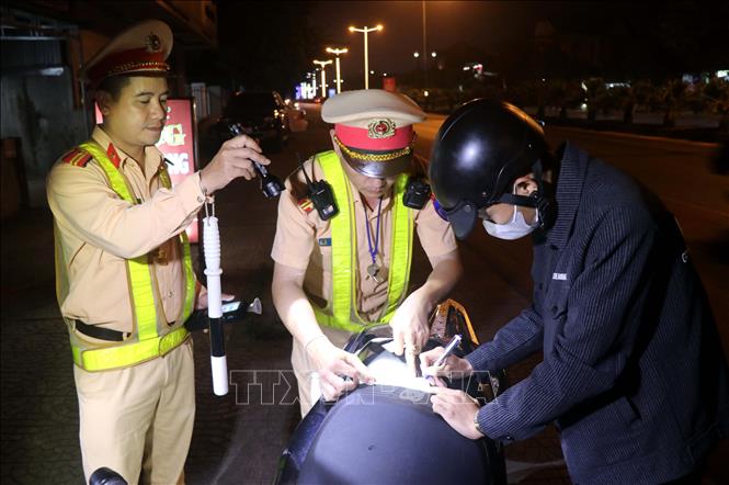 Lực lượng Cảnh sát giao thông tỉnh Quảng Trị hướng dẫn người dân ký vào biên bản vi phạm khi tham gia giao thông trên tuyến Quốc lộ 1A đoạn thành phố Đông Hà. Ảnh: Nguyên Lý/TTXVN