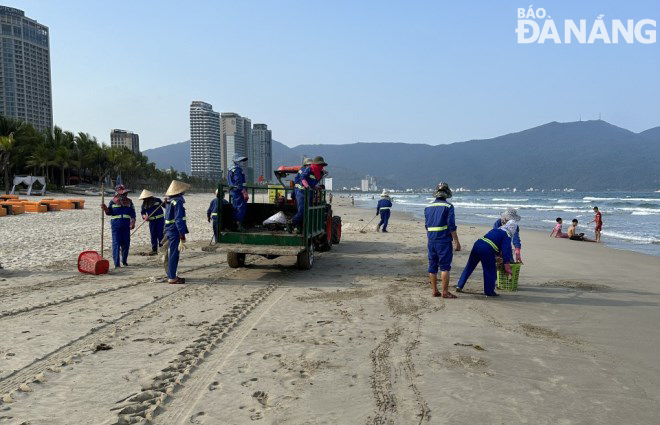 Các công nhân Xí nghiệp Môi trường Sông biển cùng phương tiện cơ giới lặng thầm dọn vệ sinh bãi biển đối diện Công viên Biển Đông.