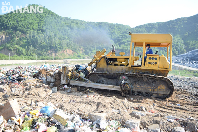 Xe ủi tiến hành san bằng đất, xà bần để phủ lên trên bề mặt rác và làm đường cho xe vận chuyển rác tiếp tục di chuyển vào vùng đổ ở bên trong.