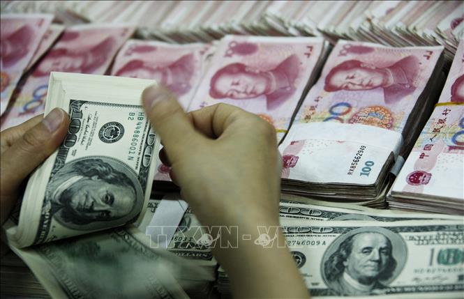 Kiểm đồng đôla Mỹ (phía trước) và đồng Nhân dân tệ tại một ngân hàng ở Hoài Bắc, tỉnh An Huy, Trung Quốc. Ảnh tư liệu: TTXVN