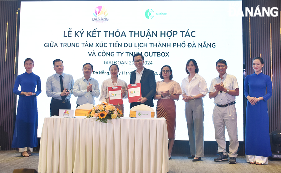 Representatives of the Da Nang Tourism Promotion Centre (4th from left) and the Outbox Co., Ltd (5th from right) signed a cooperation agreement. Photo: THU HA