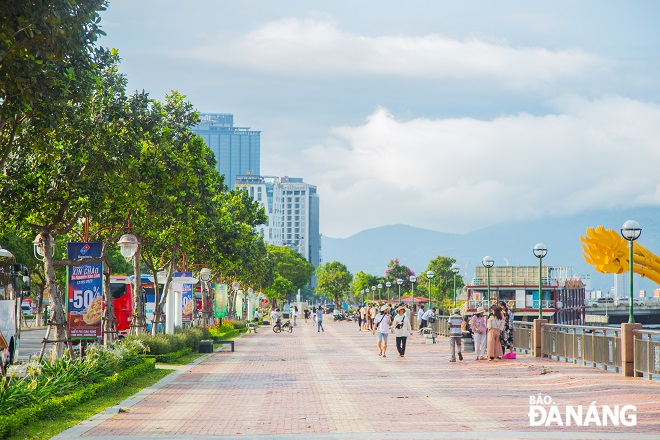 Local residents are seen going for a stroll on Bach Dang Street where the tamanu trees are planted, giving off a very attractive characteristic fragrance.