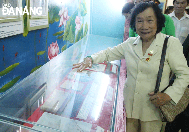 Bà Trần Thị Kim Cúc gặp lại chiếc khăn kỷ niệm của mình đang được trưng bày tại Bảo tàng Hồ Chí Minh - chi nhánh Quân khu 5. Ảnh: T.H