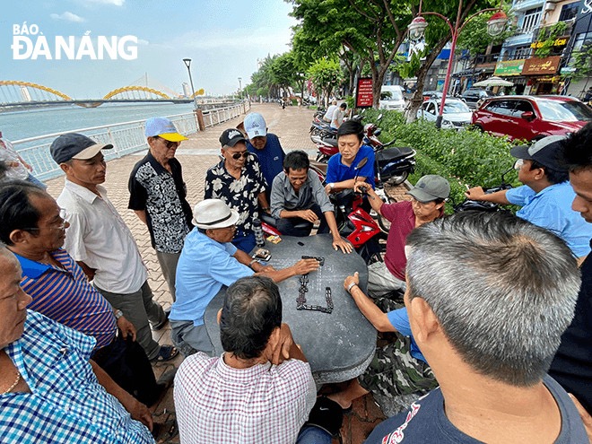 People play chess on green tree-lined roads to avoid the heat