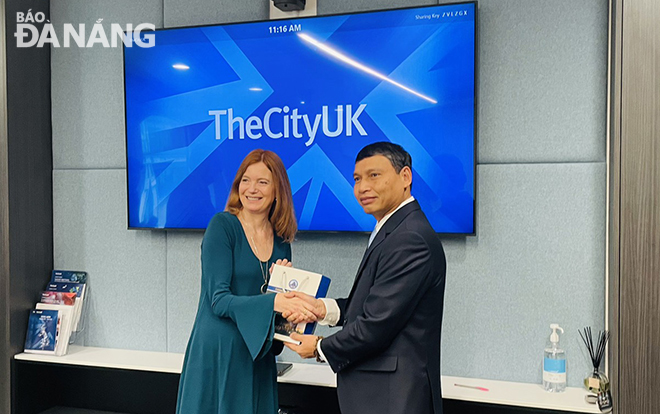 Standing Vice Chairman of the Da Nang People's Committee Ho Ky Minh (right) presenting a souvenir to leader of TheCityUK.