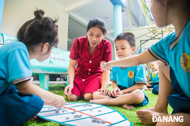 Teachers and pupils of the Hoa Phuong Do Kindergarten playing on the spacious school yard.