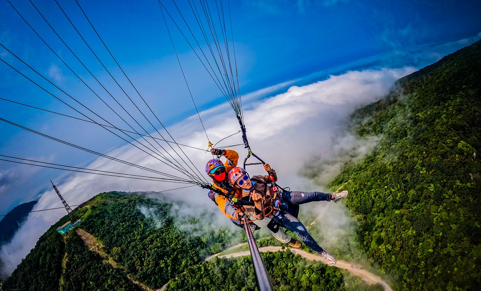 A professional accompanies and films while a tourist enjoys paragliding in Da Nang
