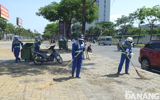 Công nhân Xí nghiệp Môi trường Sơn Trà tổng dọn vệ sinh vỉa hè đường Trần Hưng Đạo. Ảnh: HOÀNG HIỆP