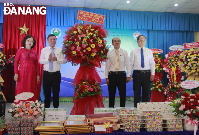 Vice Chairwoman of the Da Nang People's Committee Ngo Thi Kim Yen (first, left) Vice Chairman of the Da Nang chapter of Viet Nam Fatherland Front Committee Duong Dinh Lieu (first, right); Head of the Da Nang Party Committee's Mass Mobilisation Department Le Van Trung (second from left) presents congratulatory flowers to Hope Village on the occasion of its 30th founding anniversary. Photo: XUAN DONG