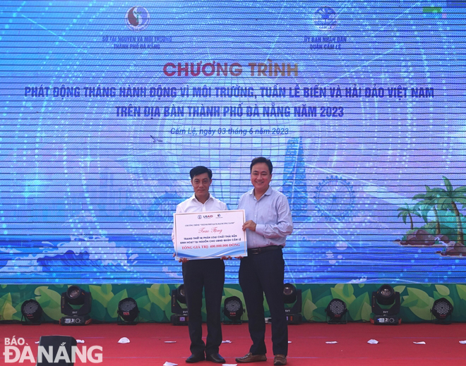 A representative from the Department of Natural Resources and Environment presents a symbolic board to support equipment and means to support in the work of sorting waste at source with a total value of VND400 million to Cam Le District, June 3, 2023. Photo: HOANG HIEP