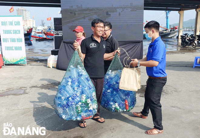 Một ngư dân mang hai bao lưới đựng các loại rác thải nhựa trong quá trình đánh bắt trên biển về giao cho Ban Quản lý âu thuyền và cảng cá Thọ Quang. Ảnh: HOÀNG HIỆP