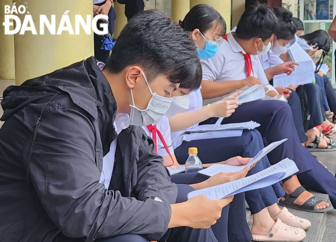 Candidates review the lessons before entering the Tran Phu Senior High School exam venue.