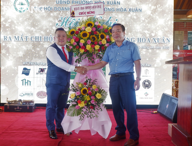 Chủ tịch UBND quận Cẩm Lệ Nguyễn Quang Vinh (phải) tặng hoa chúc mừng thành lập Chi hội doanh nghiệp phường Hòa Xuân. Ảnh: M.Q