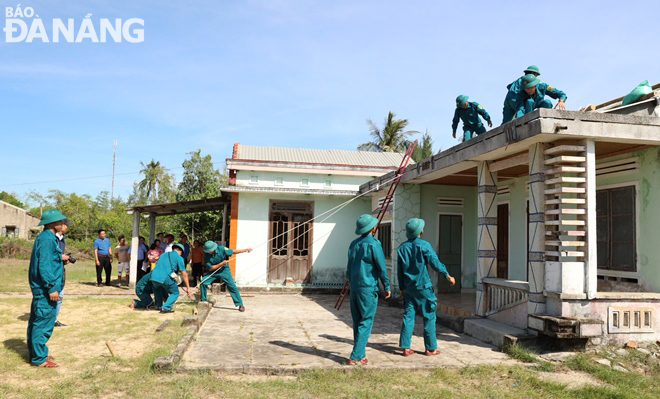 Lực lượng xung kích tham gia diễn tập giúp dân chằng chống mái nhà cửa để chống bão. Ảnh: HOÀNG HIỆP 