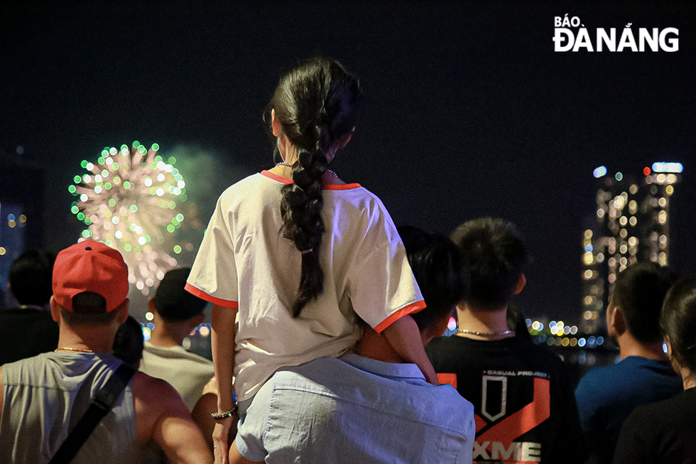 A father holding his daughter up so that she can enjoy the most beautiful fireworks display