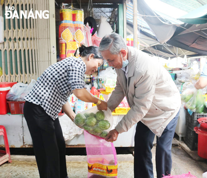 Ông Võ Văn Đức (bên phải) đang tiếp nhận phần rau, củ do tiểu thương chợ Nam Ô trao tặng.