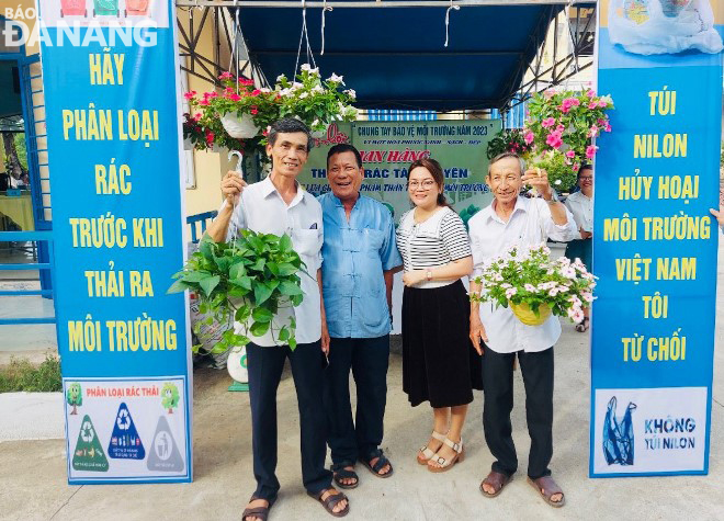 Người dân xã Hòa Phước (huyện Hòa Vang) phấn khởi nhận các giỏ hoa, cây xanh sau khi đổi rác tái chế.