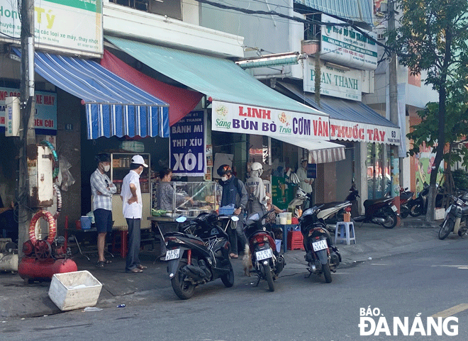 Người dân buôn bán lấn chiếm phần vỉa hè dành cho người đi bộ, khách hàng thản nhiên dựng xe máy ngay dưới lòng đường tại đường Phan Thanh. Ảnh: THÚY PHƯƠNG	