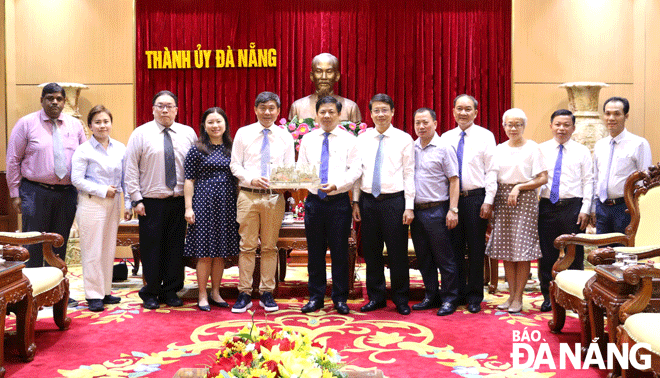 Chủ tịch HĐND thành phố Lương Nguyễn Minh Triết (thứ 7, từ phải sang) tặng quà  lưu niệm cho Giám đốc điều hành Hiệp hội Nhân dân Singapore Jimmy Toh Yong Leng (thứ 5, từ trái sang). Ảnh: T.PHƯƠNG