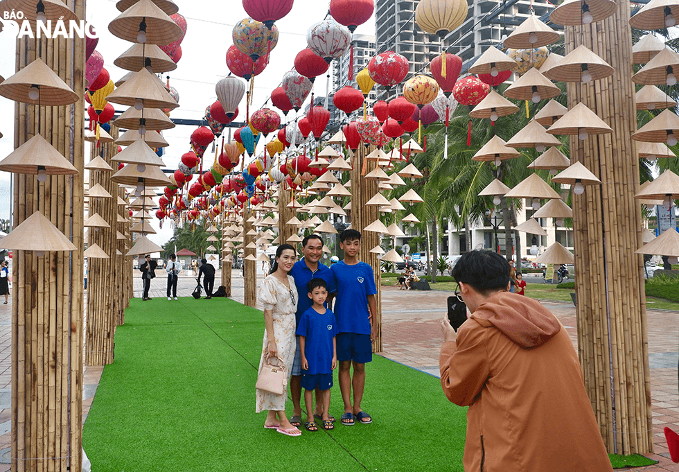 A family posing for photos at a check-in point in the East Sea Park within the framework of the Viet Nam - Japan Festival.