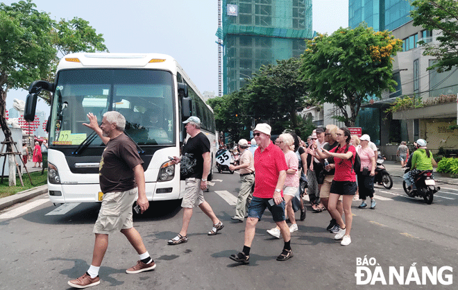 Tourism firms hope that relevant ministries, departments and agencies will soon have instructions to implement the new policies. IN THE PHOTO: International tourists are seen crossing Bach Dang Street. Photo: T.H