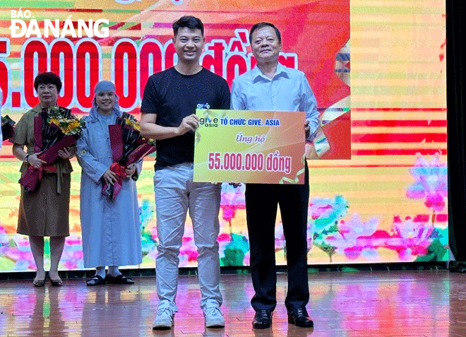 Vu Xuan Thanh (left) donates VND55 million to support the city's Care Center for AO Victims and Unfortunate Children. Photo: LE HUNG