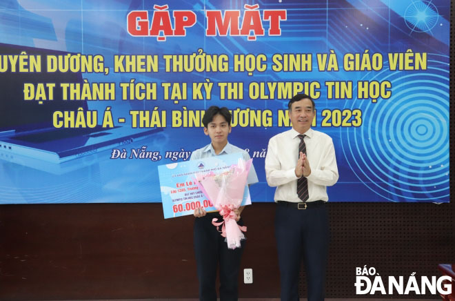 Chủ tịch UBND thành phố Lê Trung Chinh (phải) tặng bằng khen cho học sinh Lê Ngọc Bảo Châu. Ảnh: NGỌC HÀ
