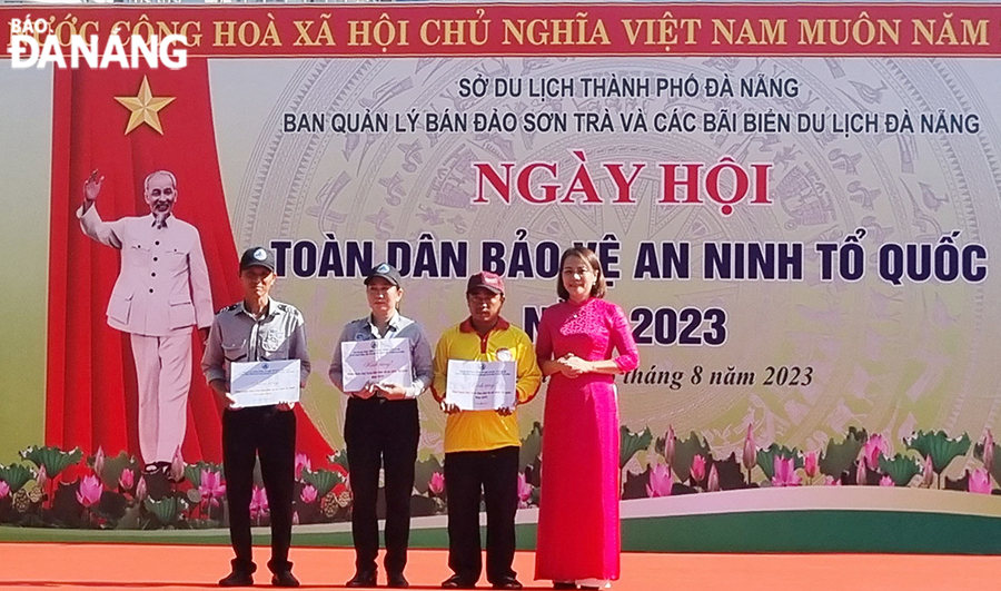 Vice Chairwoman of the Da Nang Fatherland Front Committee Tran Thi Man (first, right) presents gifts to 3 outstanding individuals in building the movement of all people to protect national security. Photo: THU HA