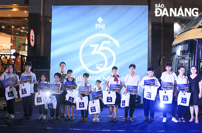 Phó Chủ tịch Hội LHPN thành phố Nguyễn Thị Huyền (áo trắng, giữa) trao quà cho các em học sinh có hoàn cảnh khó khăn trên địa bàn thành phố.