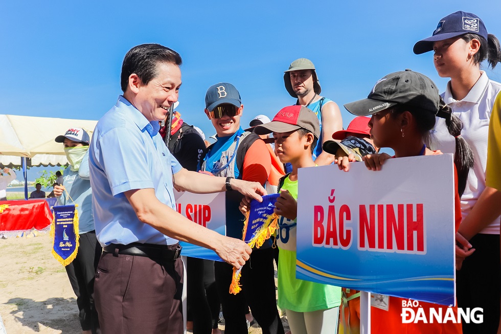 Director of the Da Nang Department of Culture and Sports Pham Tan Xu presenting souvenir flags to participating teams.