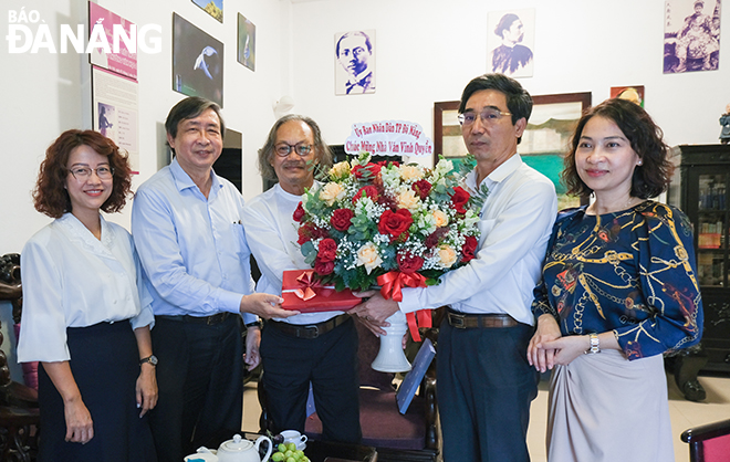 Vice Chairman of the Da Nang People's Committee Tran Chi Cuong (2nd, right) presents flowers to congratulate writer Vinh Quyen (middle). Photo: X.D