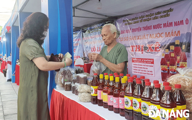 Locals and tourists buy Nam O fish sauce products at the farmers market in Hoa Vang District