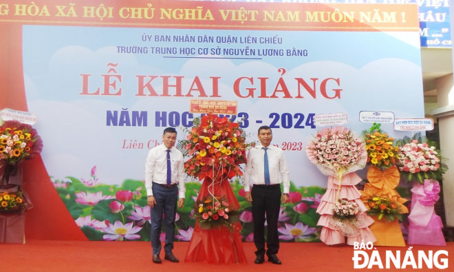 Phó Chủ tịch Thường trực UBND thành phố Hồ Kỳ Minh (phải) tặng lẵng hoa chúc mừng Trường THCS Nguyễn Lương Bằng. Ảnh: CHÂU ANH
