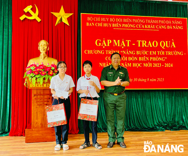 Đại tá Trần Công Thành (bên phải) trao quà cho các học sinh có hoàn cảnh khó khăn trên địa bàn . Ảnh: BÁ VĨNH