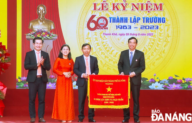 Chủ tịch UBND thành phố Lê Trung Chinh (bên phải) trao cờ cho nhà trường. Ảnh: NGỌC HÀ