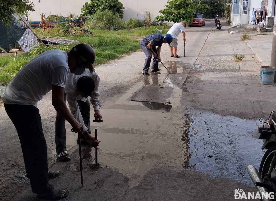 Người dân phường Mân Thái (quận Sơn Trà) khơi thông các lỗ thu nước mưa trên một đường kiệt.