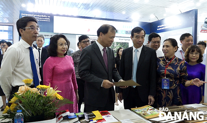 Deputy Minister of Industry and Trade Do Thang Hai (3rd, left) and Da Nang People's Committee Chairman Le Trung Chinh (4th, left) get a look at products at booths.