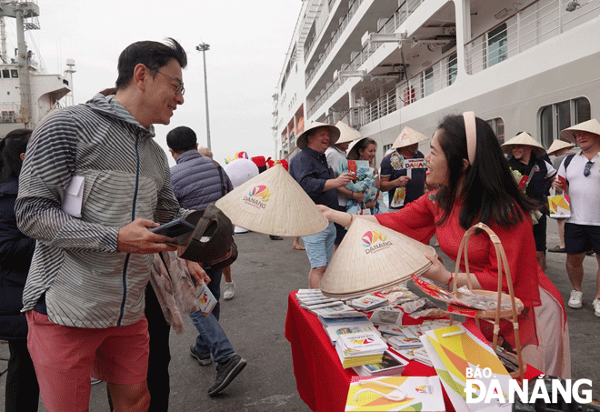 A staff member of the Da Nang Tourism Promotion Center giving conical hats to international tourist arrivals in the city. Photo: M.Q