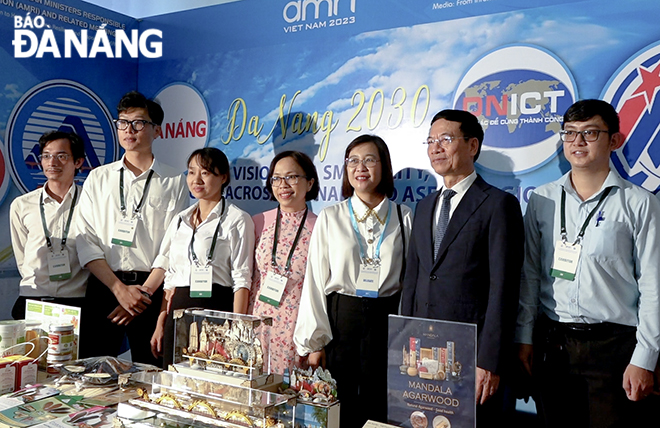 Minister of Information and Communications Nguyen Manh Hung (second, right) takes a souvenir photo at the Da Nang booth.