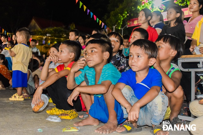 Many children attentively watching the lion dance and music performances