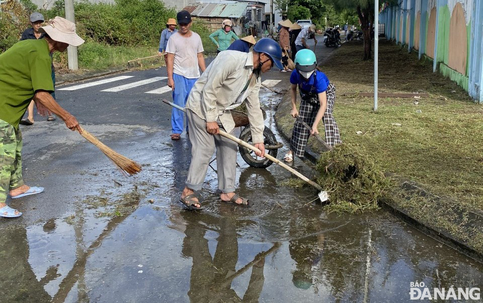 Người dân ở một khu tái định tại xã Hòa Liên (huyện Hòa Vang) ra quân tổng dọn vệ sinh môi trường kết hợp khơi thông cửa thu nước mưa trên đường.