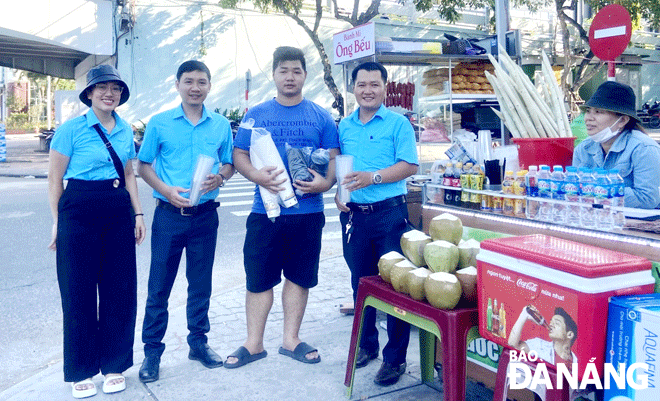 Bí thư Đoàn cơ sở Công ty CP Môi trường đô thị Đà Nẵng Lê Xuân Anh (thứ 2, bên phải sang) có nhiều ý tưởng bảo vệ môi trường như phối hợp phát ly giấy cho các hàng quán tại khu vực đông du khách. Ảnh: M.Q