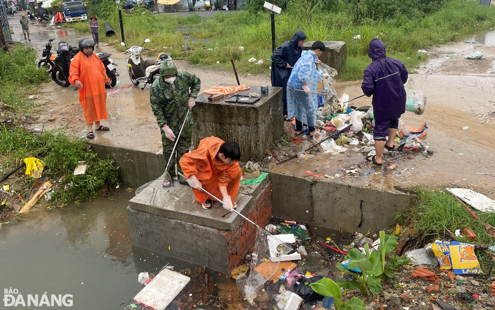 Các lực lượng sử dụng vợt để vớt rác, khơi thông thoát nước tại khu vực cống Khe Cạn (quận Thanh Khê).